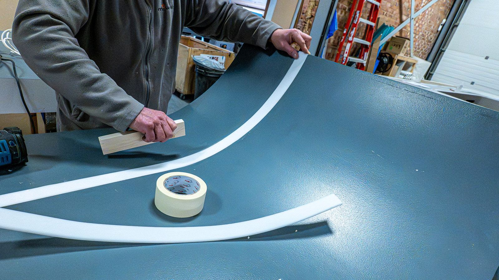 Hands shaping a curved exhibition panel during production